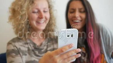 两个迷人的混血模特坐在咖啡馆里，用手机看有趣的视频。生活方式高清慢动